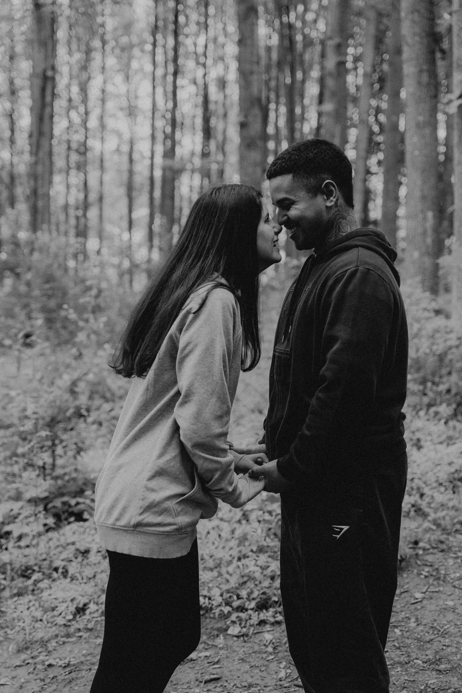 Engaged couple laughing together in the woods