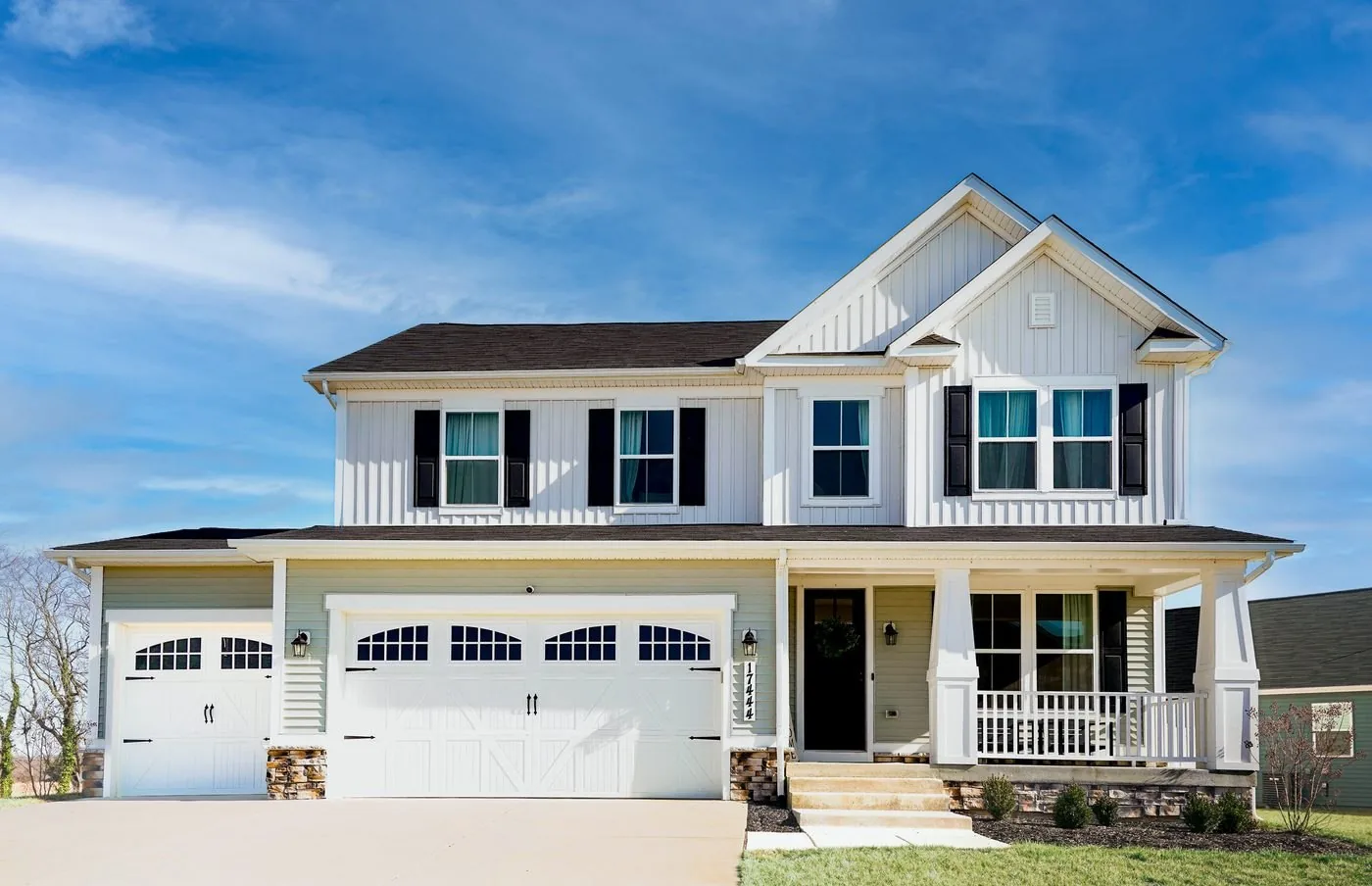 Two-story house exterior with white siding and covered porch