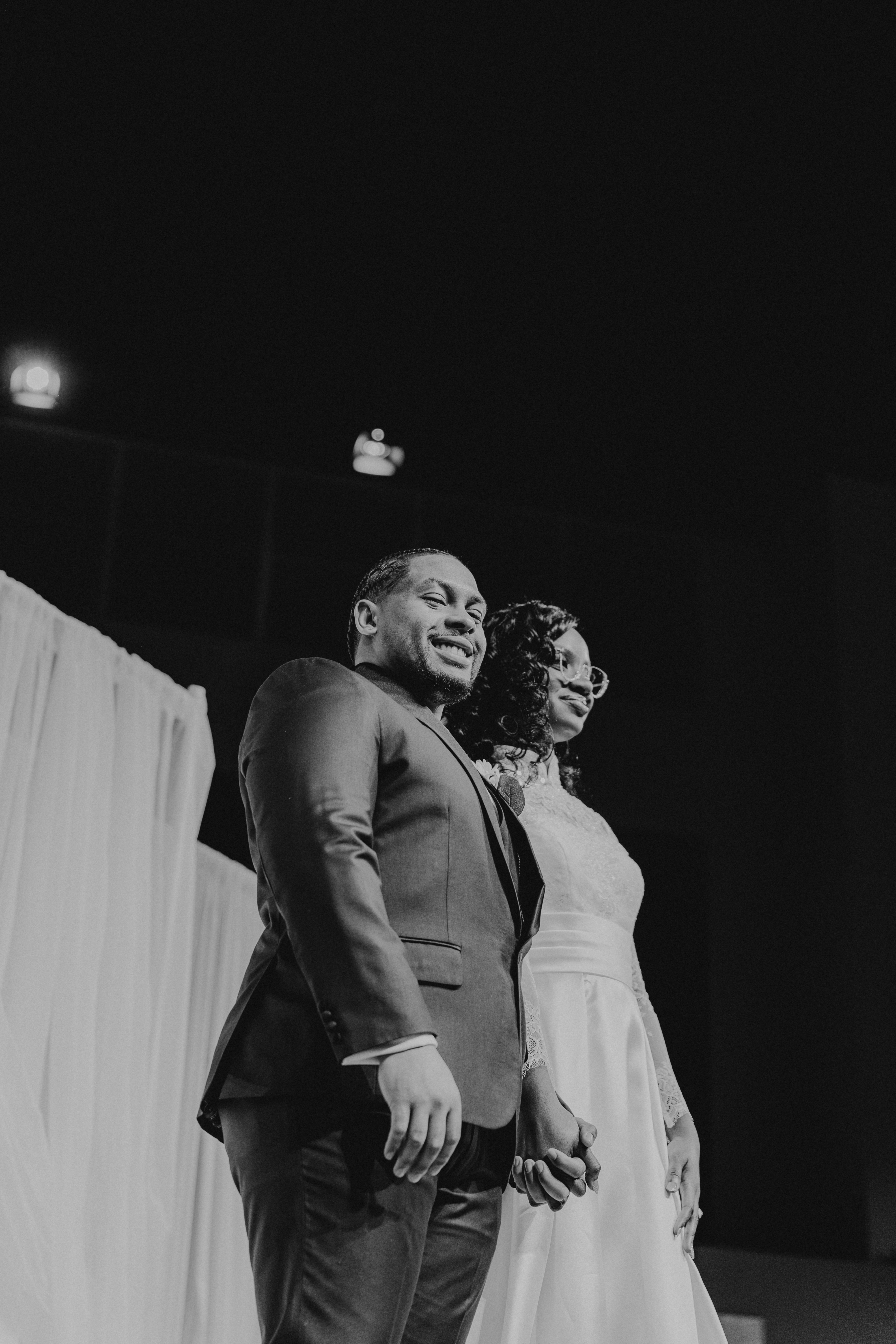 Bride and groom smiling on stage at their reception
